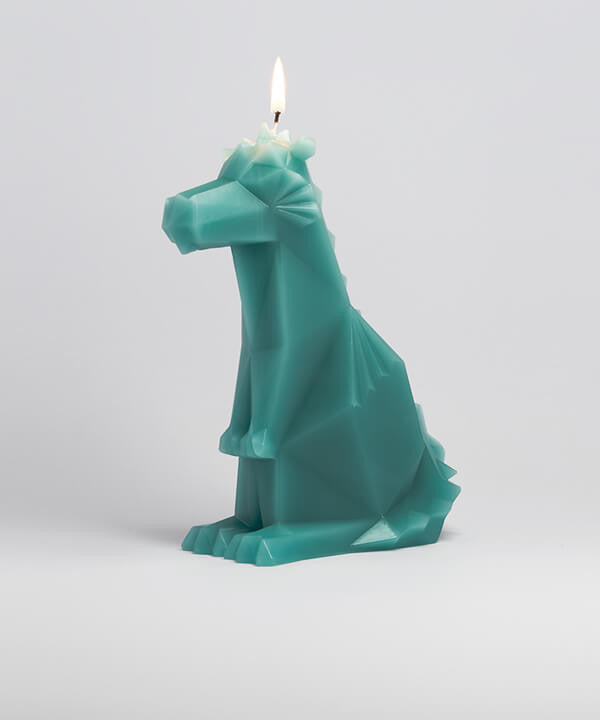 Side view of green dreki the dragon shaped pyropet candle with a burning wick. 