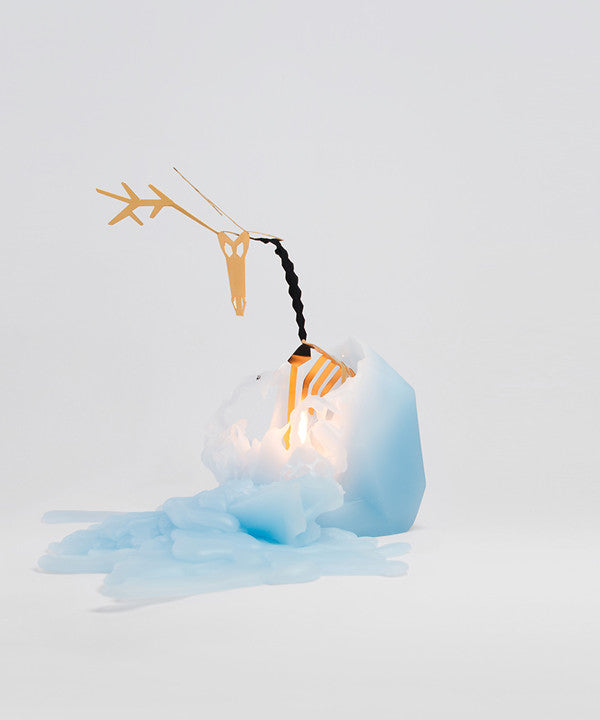 Side view of light blue dyri reindeer pyropet candle. It has been lit and is melting to reveal inner skeleton surprise. 