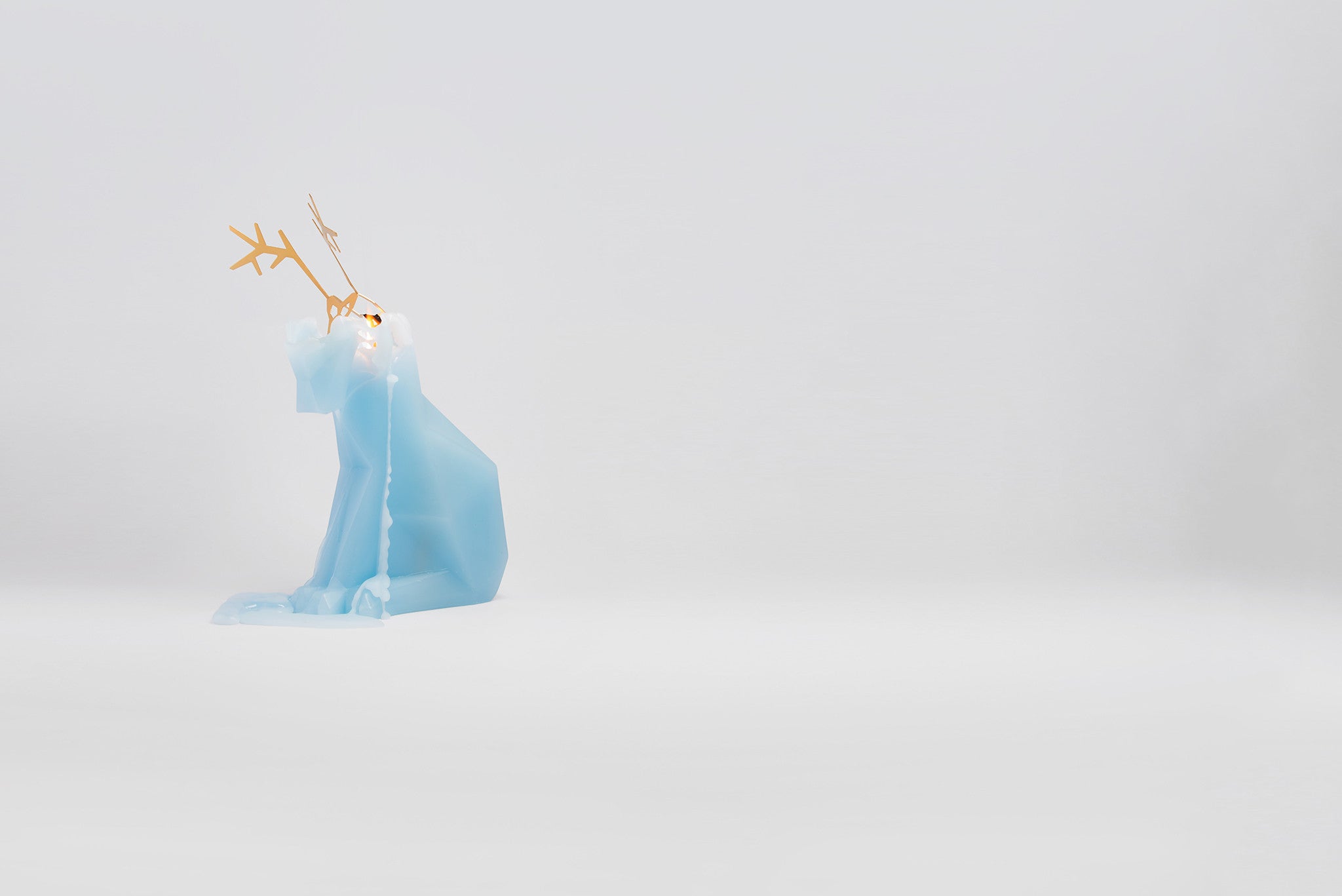 Side view of melting light blue reindeer pyropet candle. As the wax melts, the candle reveals an inner skelton frame. 