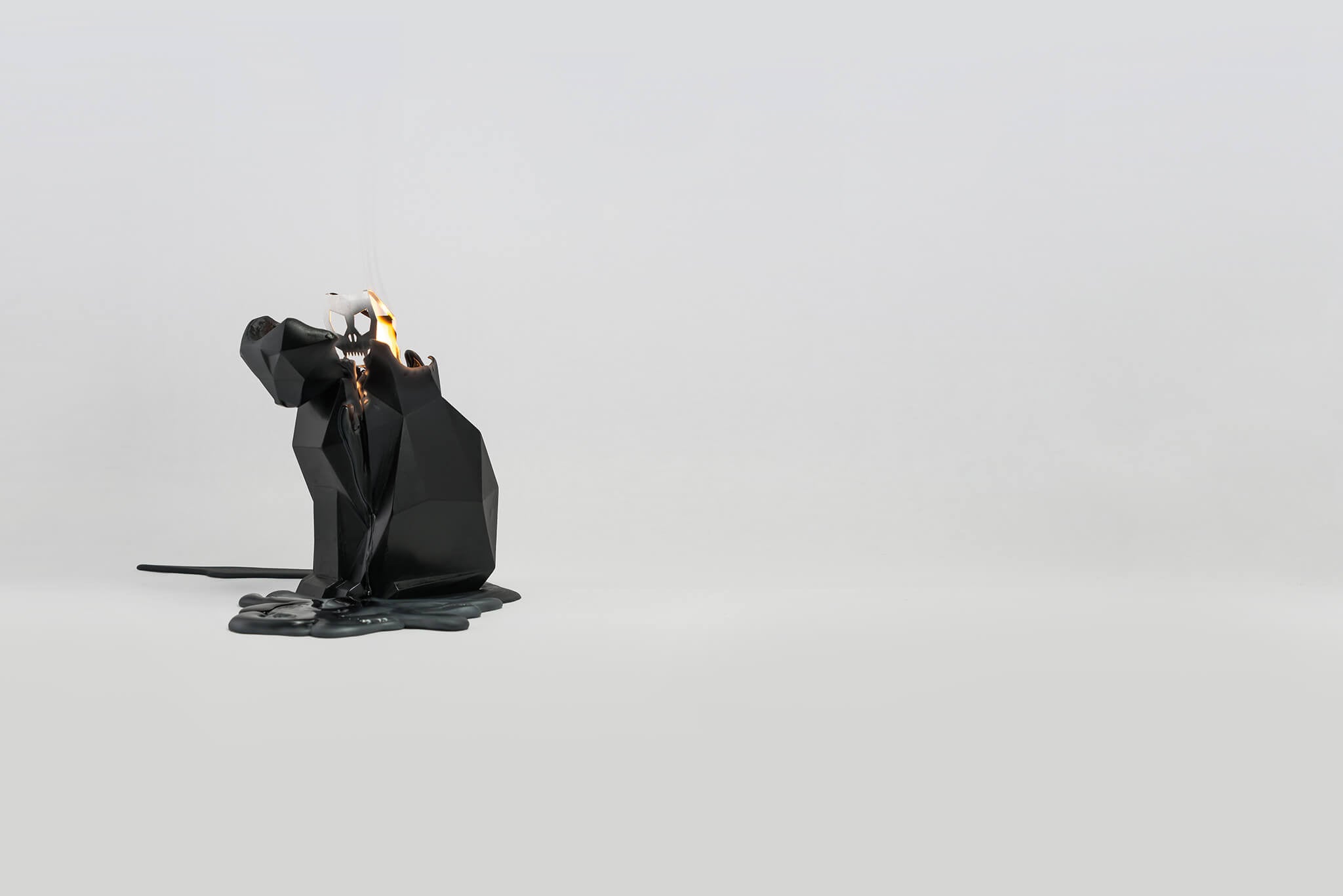 Side view of a melting black kisa the cat shaped pyropet candle. 