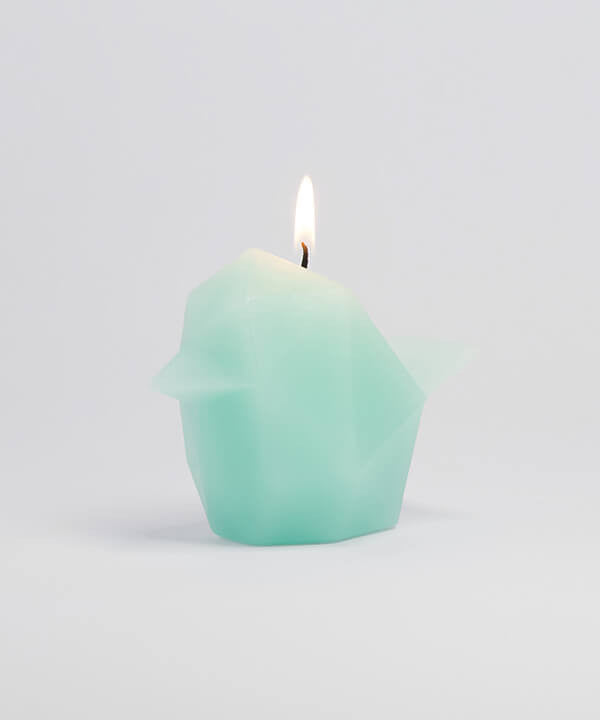 Side view of mint bird shaped pyropet candle that has a burning wick. 