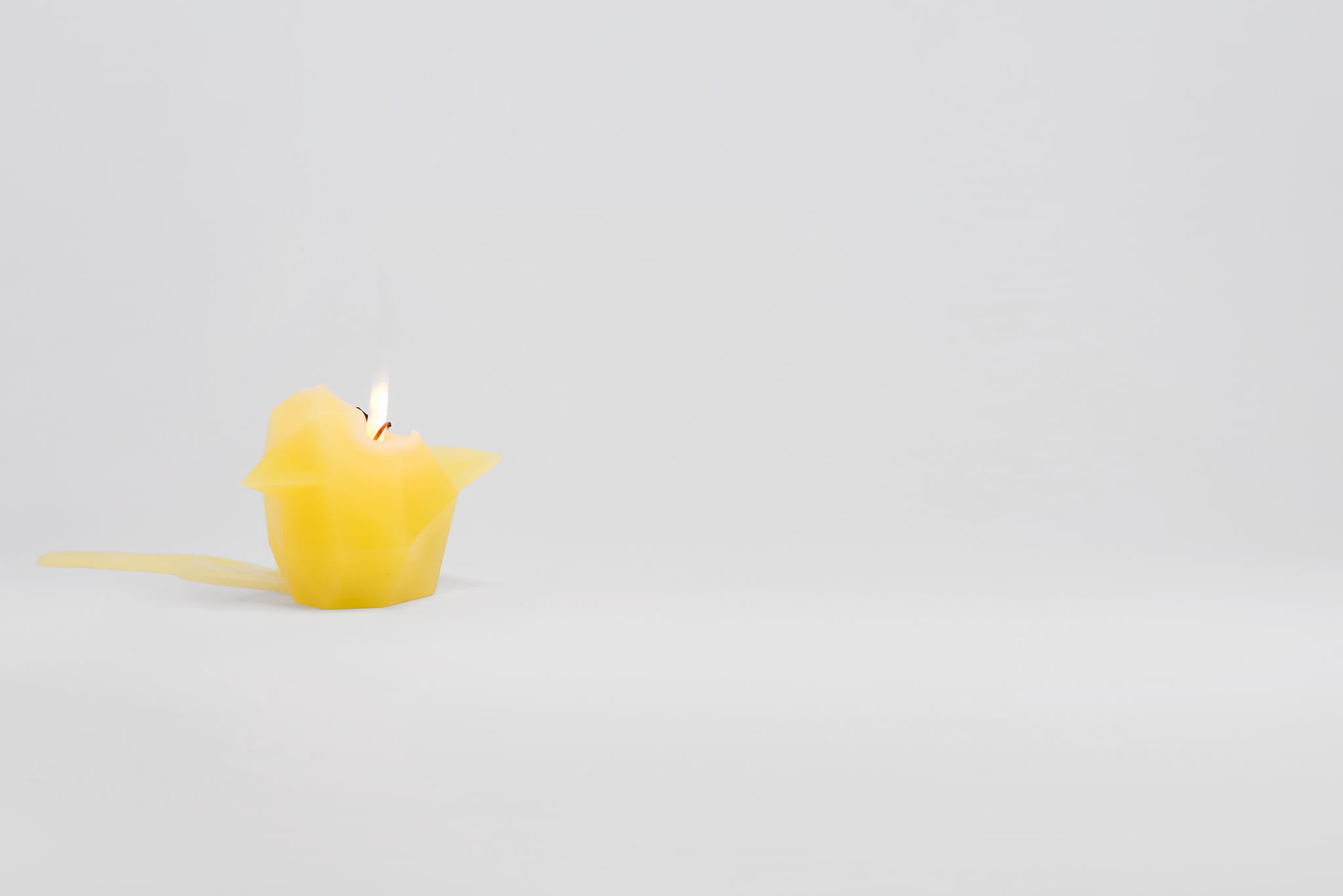 Side view of vibrant yellow bird shaped pyropet candle that has a lit wick. 