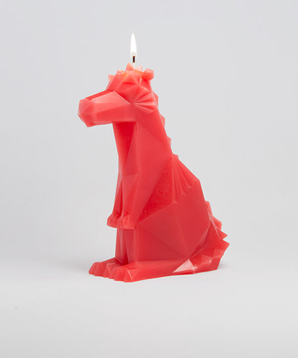 Side view of red dreki propet dragon candle. The wick is lit. 