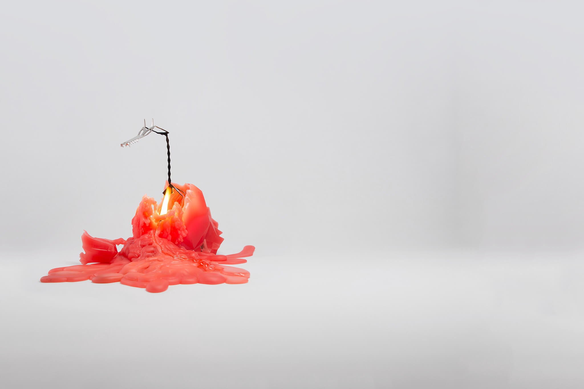 Red dragon shaped pyropet candle reveals a metal skeleton frame while it melts.