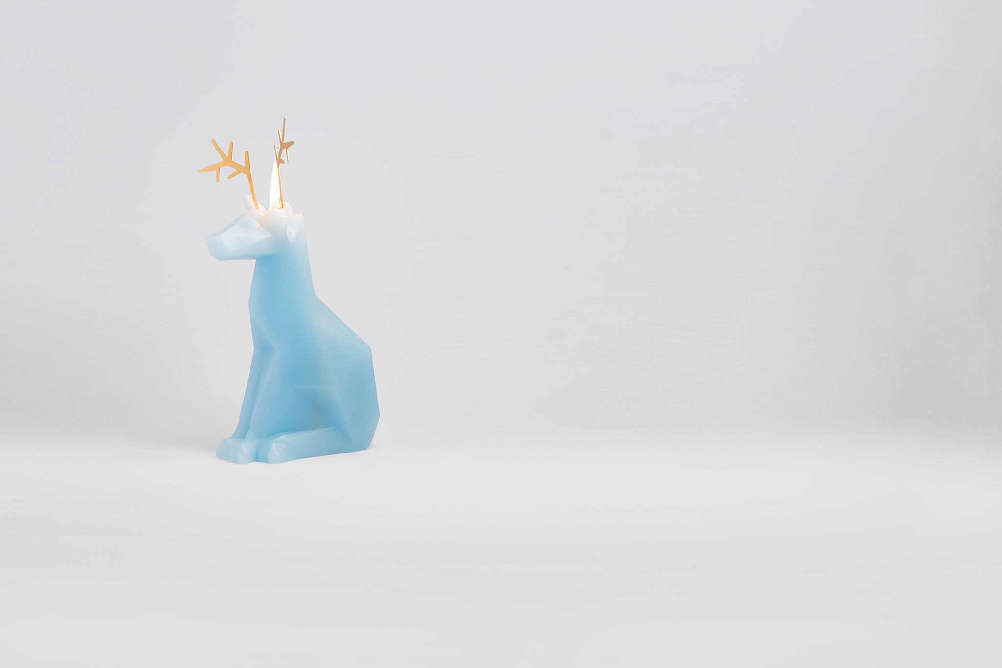 Side view of light blue dyri reindeer pyropet candle with the wick burning.