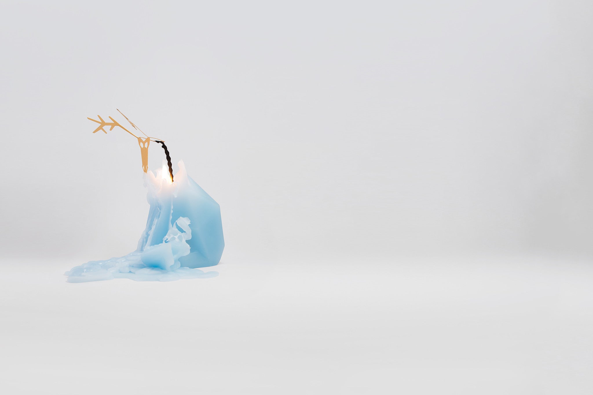 Side view of melting light blue reindeer pyropet candle. As the wax melts, the candle reveals an inner skelton frame.