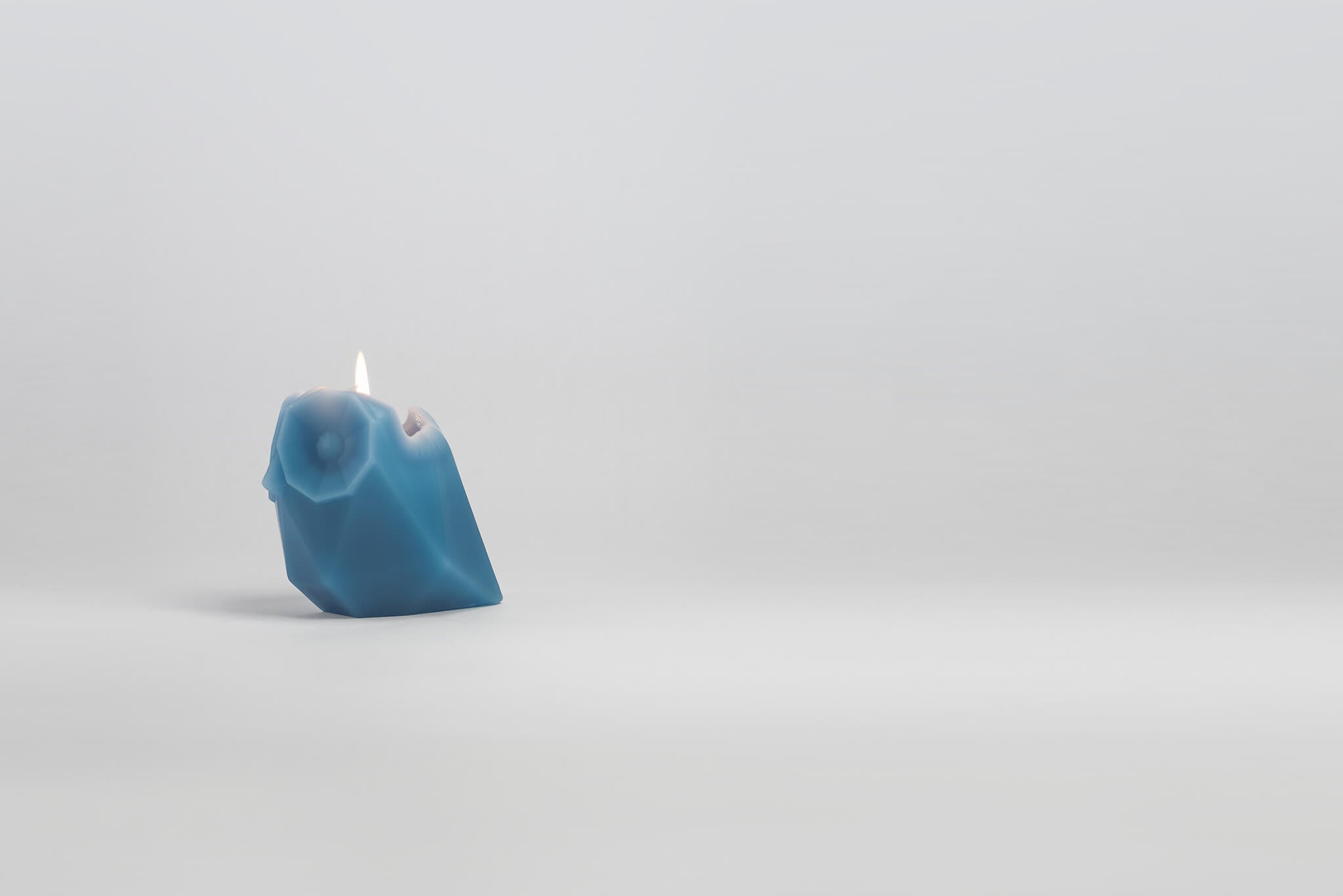 Side view of melting blue owl shaped pyropet candle. 